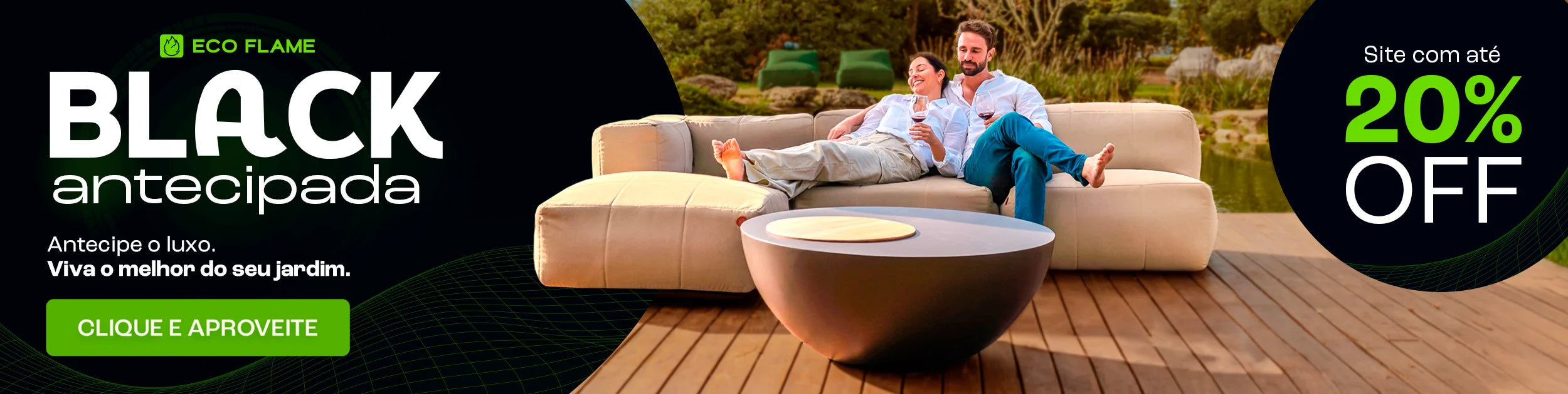 Casal sentado em um sofá cinza em uma sala de estar aconchegante. Eles estão sorrindo e segurando canecas laranja. No fundo, uma estante com livros e objetos decorativos. No topo da imagem, o texto 'Mês dos NAMORADOS' com um coração laranja, e à direita, um banner laranja com o texto 'Site até 35% OFF +30 DIAS PARA TESTAR'. O casal está usando meias coloridas e parecem estar relaxados e felizes.